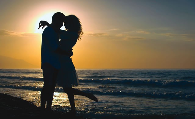 Couple embracing at sunset on the beach — meet local singles free on EzHookups